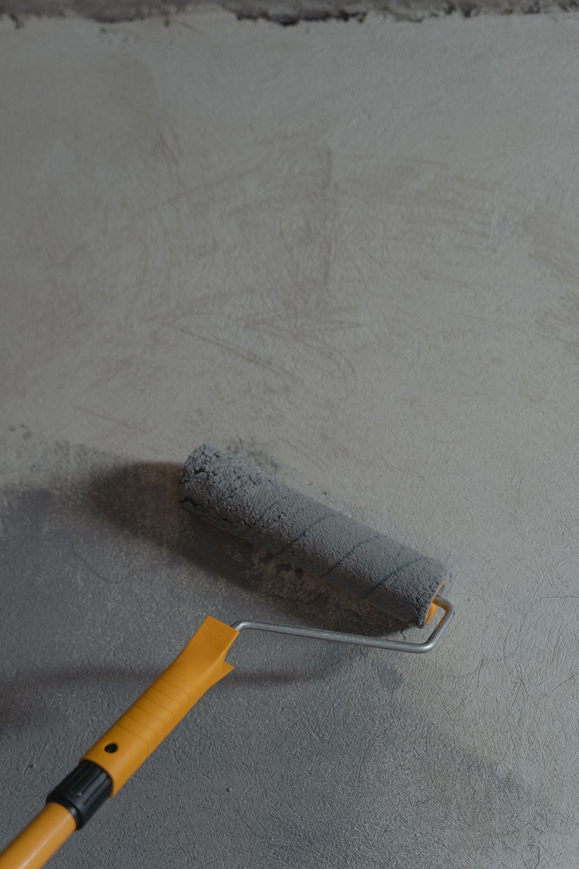 Close-up of a paint roller applying gray paint on a wall, ideal for renovation themes.